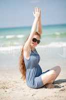 Woman raising her hands doing exercises on the beach sand