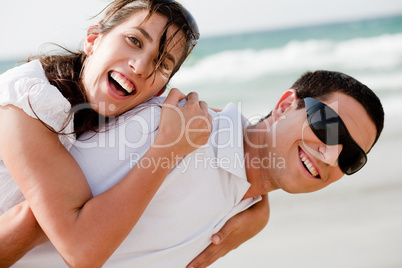 Playful young couple smiling on the beach