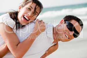 Playful young couple smiling on the beach
