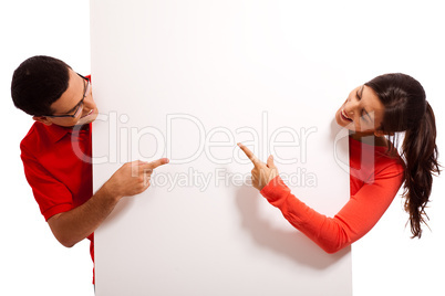 Playful young couple pointing the blank white baord