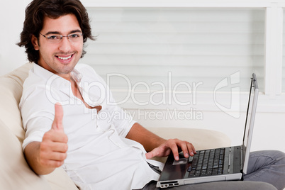 young man using laptop showing thumbs up