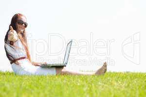 young feamle sit in the park and using a laptop