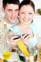 Happy couple preparing spaghetti in the kitchen and drinkng wine