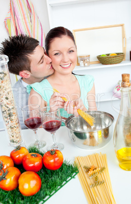 Bright couple preparing spaghetti in the kitchen and drinkng win