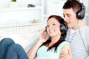 Charming caucasian couple listening to music wearing headphones