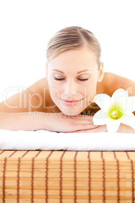 Close-up of a delighted woman lying on a massage table with a fl