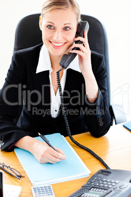 Self-assured businesswoman talking on phone and writing in her o