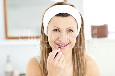 Delighted young woman using a red lipstick in the bathroom