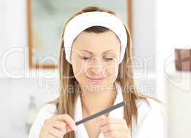 Happy woman using a nail file wearing a bath robe standing in th