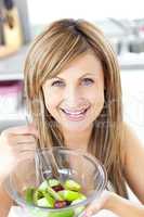 Smiling woman eating a fruit salad smiling at the camera in the