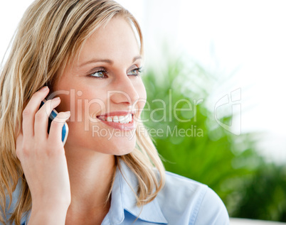 Bright businesswoman talking on phone sitting on a sofa