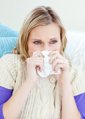 Morbid woman using a tissue sitting on a sofa