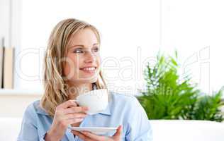 Captivating businesswoman holding a cup sitting on a sofa