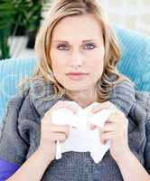Diseased woman using a tissue sitting on a sofa
