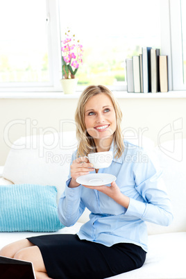 Smiling businesswoman holding a cup of coffee sitting on a sofa