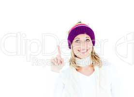 Young caucasian woman wearing a colorful hat pointing upwards wi