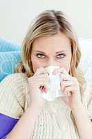 Morbid woman using a tissue sitting on a sofa at home