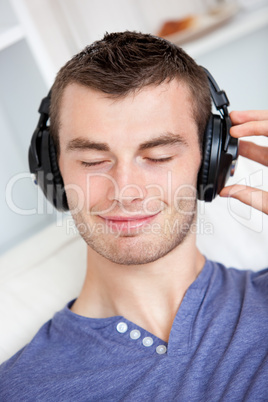 Lively young man listening to music sitting on the couch in the