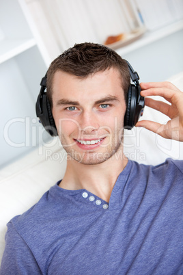 Bright young man listening to music sitting on the couch in the