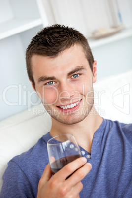 Animated young man drinking wine looking at the camera sitting o