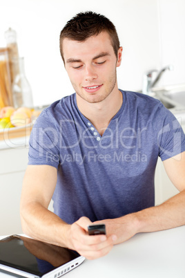 Positive young man sending a text in the living-room