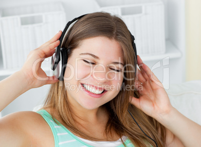 Cheerful young woman listening to music with headphones on a sof