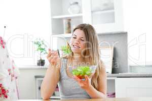 Charming woman eating a salad in the kitchen