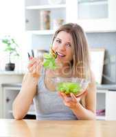 Bright woman eating salad in the kitchen