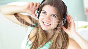 Cheerful caucasian girl listening to music sitting on a sofa