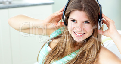Charming caucasian girl listening to music sitting on a sofa