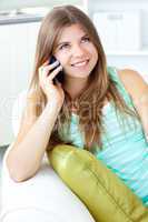 Positive woman talking on phone sitting on a sofa