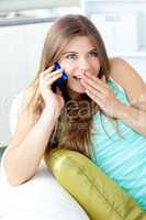 Merry woman talking on phone sitting on a sofa