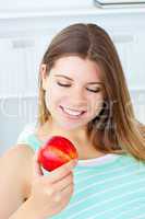 Charming caucasian woman holding an apple sitting on a sofa
