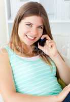 Radiant woman talking on phone sitting on a sofa