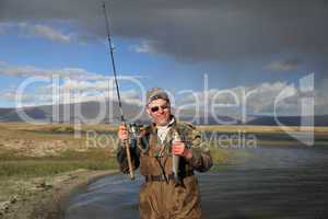 Fisherman with spinning catching fish in mountain lake Dayan Nuu