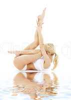 fit blond in white underwear practicing yoga on sand