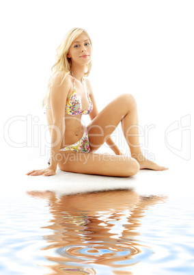 blond in bikini sitting on white sand