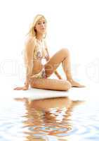 blond in bikini sitting on white sand