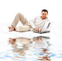 relaxed man with laptop on white sand