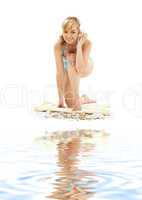 blond in blue bikini with shell on white sand