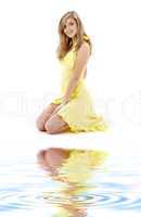 kneeled girl in yellow dress on white sand