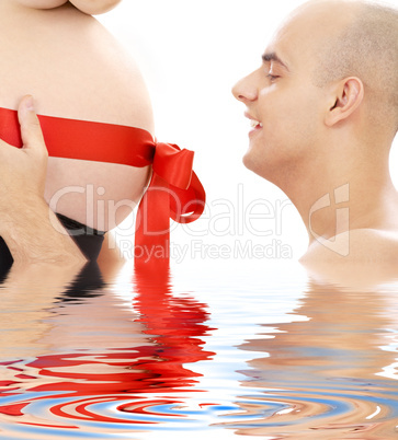 proud father and belly with red ribbon in water