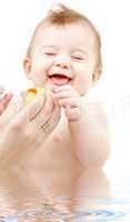 laughing baby boy in water playing with rubber duck