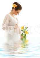 pregnant woman with yellow lily in water