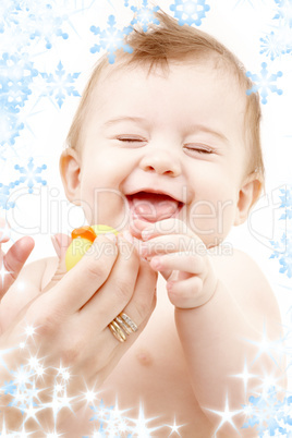 laughing baby boy in mother hands with rubber duck