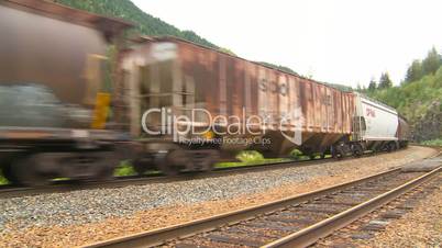 Canadian freight train in the mountains, pan to bridge.
