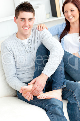 Nice boyfriend massaging his girlfriend's feet on the sofa