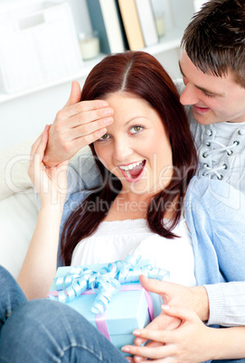 Surprised girlfriend being offered a present by her boyfriend in