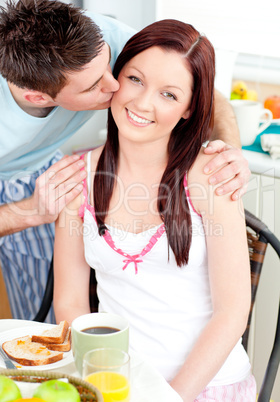 Handsome boyfriend kissing his charming girlfriend during breakf