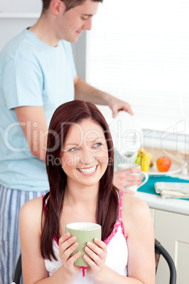 Joyful woman drinking coffee and smiling in the kitchen